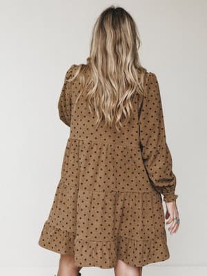 Shot from the back, this polka dot mini dress in warm mocha has a relaxed, tiered silhouette with long blouson sleeves — the kind of dress that looks intentional with boots and a turquoise ring.