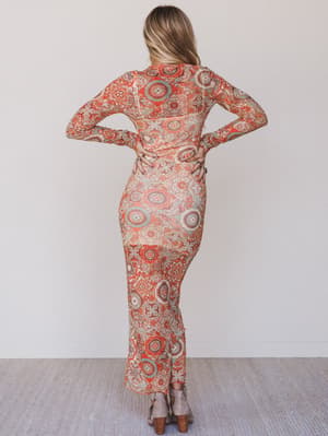 Woman wearing a patterned dress standing against a plain background
