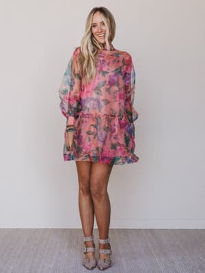 Woman wearing a colorful floral dress against a plain background