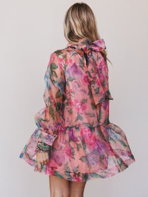 Woman wearing a colorful floral dress against a plain background