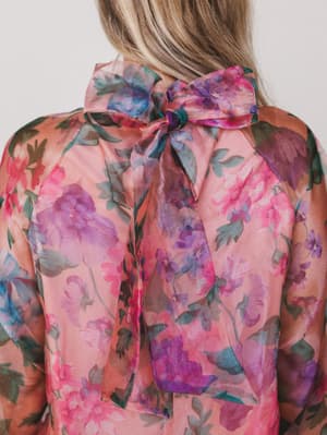 Floral blouse with a bow detail on a plain background