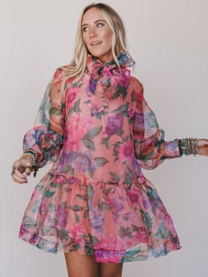 Woman wearing a colorful floral dress against a plain background