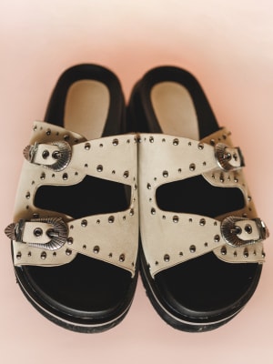 Pair of sandals with decorative straps on a pink background