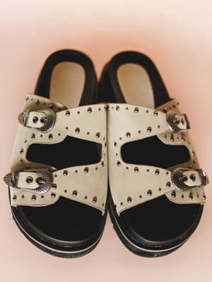 Pair of sandals with decorative straps on a pink background
