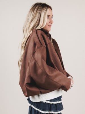 Woman wearing a brown jacket with a plain background