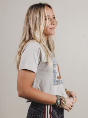 Woman wearing a gray t-shirt with a colorful graphic design on a plain background