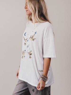 Person wearing a white t-shirt with bird illustrations on a plain background