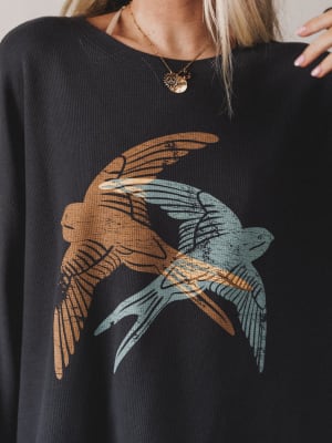 Black sweater with bird design worn by a person