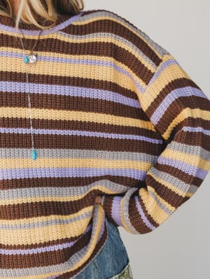 Close-up of a person wearing a striped sweater with brown, yellow, and purple colors.