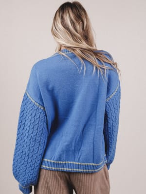 Person wearing a blue quilted jacket with a neutral background