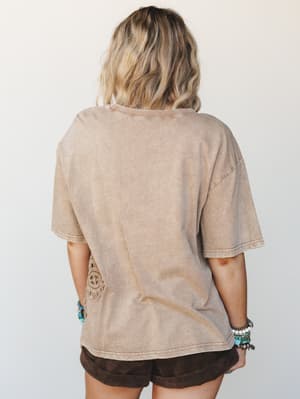 Shot from the back, this washed mocha oversized tee has a relaxed, lived-in feel — accented with a tonal crochet appliqué at the hip and styled with dark chocolate shorts and layers of turquoise and beaded bracelets.