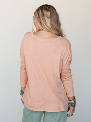 Shot from the back, a relaxed long sleeve tee in washed dusty rose pairs effortlessly with sage wide-leg pants and layers of turquoise and beaded bracelets — the kind of outfit that looks like it came together without trying.