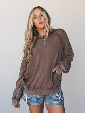 A relaxed, lived-in pullover hoodie in a warm washed cacao brown paired with blue camo shorts — the kind of outfit that looks effortless because it actually is.