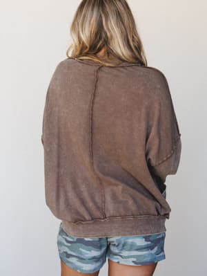 Shot from the back, this washed-out cocoa sweatshirt has that perfectly broken-in feel — relaxed seaming, a banded hem, and just enough lived-in texture to make it look like something you've loved for years, paired with blue camo shorts for a casual,