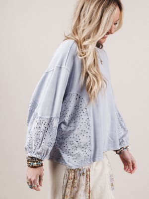 Woman wearing a light blue blouse with sheer sleeves against a beige background