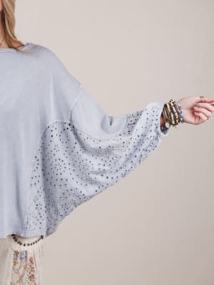 Light blue blouse with bell sleeves worn by a person on a beige background