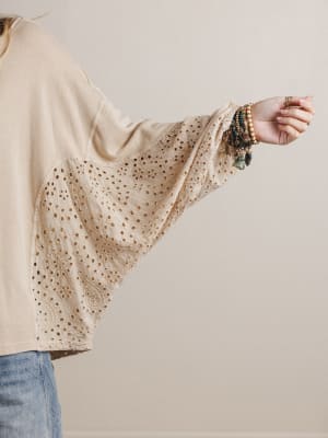 Beige blouse with bell sleeves worn by a person, against a plain background
