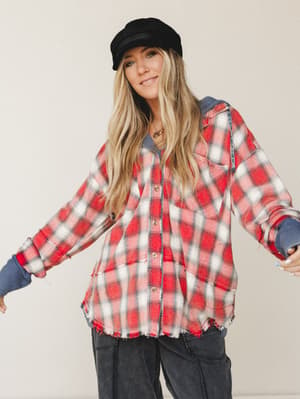 A relaxed, lived-in plaid shacket with raw-hem edges and waffle-knit hood detail, styled with dark cargo pants and a baker boy cap — the kind of outfit that looks effortless but absolutely has a whole personality behind it.