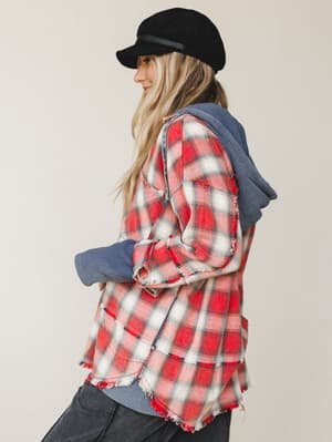 Shot from the back at a three-quarter angle, this lived-in plaid flannel jacket with a contrast waffle-knit hoodie insert has that effortless 'grabbed it off the chair on the way out' energy — styled with dark jeans and a black baker boy cap.