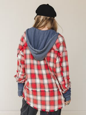 Shot from the back, a model in a red plaid flannel jacket layered over a slate blue waffle-knit hoodie — the kind of outfit that looks like it came together effortlessly on a Sunday morning and ended up being the whole vibe.