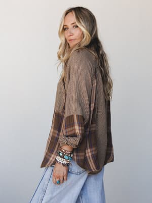 A relaxed, lived-in mixed-plaid top styled with wide-leg light wash jeans and a stack of turquoise and beaded bracelets — the kind of outfit that looks effortless but is clearly very intentional.