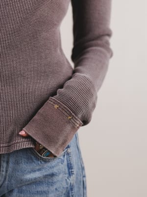 Close-up of a person wearing a brown ribbed sweater with a blurred background