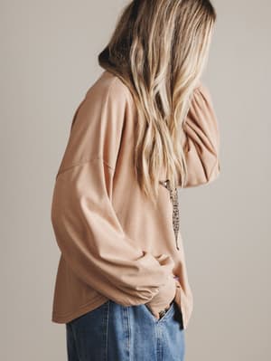Woman wearing a blush-colored oversized shirt with a star pattern on a plain background