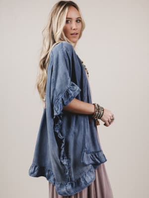Woman wearing a blue denim kimono-style top against a beige background