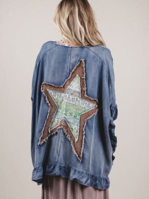 Denim jacket with a star-shaped patch on the back, worn by a person.