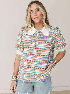A striped floral-print top with a sweet peter pan collar and puff sleeves styled with light wash jeans and stacked bracelets — the kind of top that makes a Tuesday feel a little more intentional.