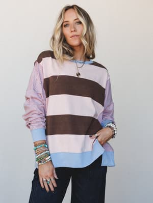 A relaxed mixed-fabric pullover top styled with stacked beaded bracelets and layered necklaces — the kind of top that looks like you tried just enough and somehow nailed it.