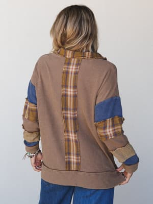 A back-view shot of a relaxed patchwork thermal top in camel, layered with frayed plaid and denim fabric panels across the sleeves and center back — the kind of top that looks like it has a whole personality before you even turn around.