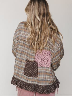 A back-facing shot of a relaxed plaid top with patchwork floral panels and a ruffle hem — the kind of piece that looks like it came from your most stylish friend's vintage haul.