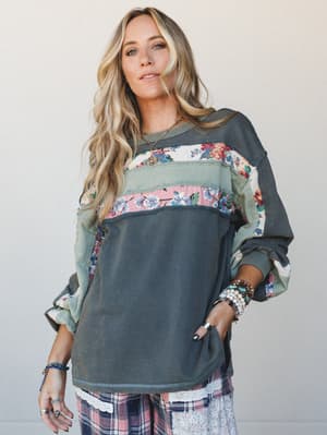 A relaxed, patchwork-style sweatshirt top with floral and solid fabric panels layered over plaid wide-leg pants — the kind of outfit that looks like it came together effortlessly but clearly didn't.