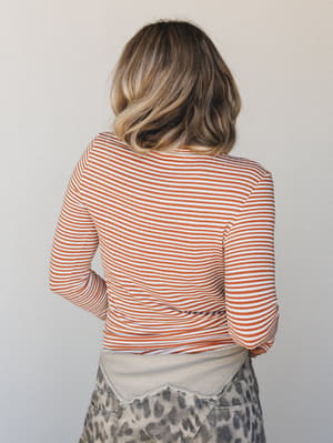 A back-view shot of a rust-striped long sleeve fitted top layered over a leopard print mini skirt — casual and a little unexpected, the kind of mix-and-match that looks effortless without trying.