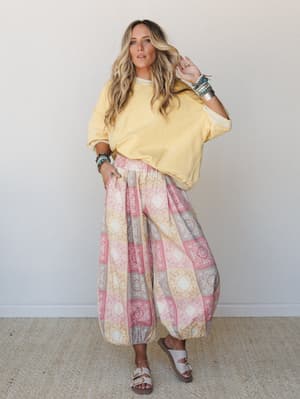 A breezy, sun-washed look pairing an oversized butter-yellow sweatshirt with voluminous printed harem pants — the kind of outfit that feels equally at home on a slow morning walk or a weekend market run.