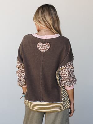 Shot from behind, this mixed-media sweatshirt top layers a coffee brown fleece body with floral puff sleeves, a striped hem panel, pink ribbed trim, and a floral heart appliqué at the back — the kind of top that looks like it was made from all your f