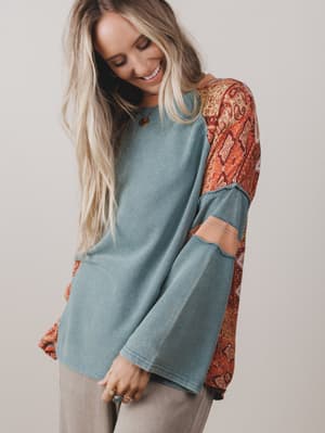Woman wearing a blue and patterned long-sleeve top against a plain background
