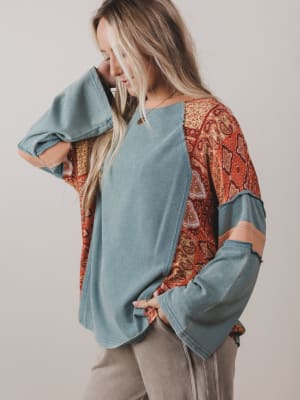 Woman wearing a blue top with patterned sleeves against a plain background