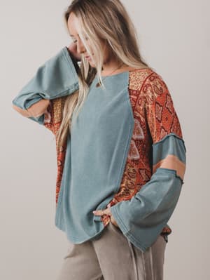 Woman wearing a blue top with patterned sleeves against a plain background