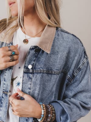 Person wearing a denim jacket with a neutral background