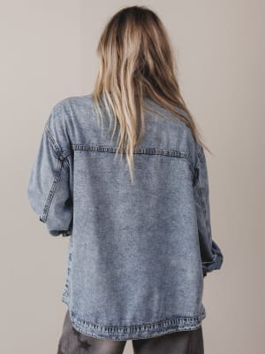 Person wearing a denim jacket from behind on a plain background