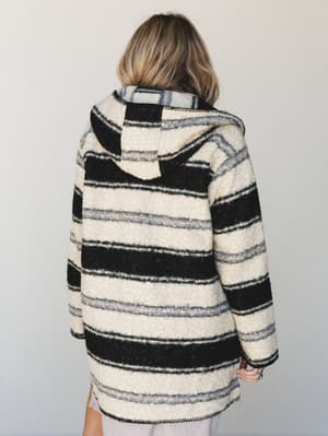 Shot from the back, this oversized striped jacket has a cozy, lived-in feel — the kind of layer that looks like it belongs on a road trip or a slow Saturday morning.