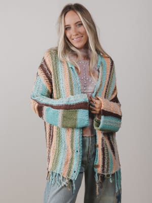 Woman wearing a colorful striped cardigan against a plain background