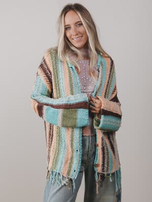 Woman wearing a colorful striped cardigan against a plain background