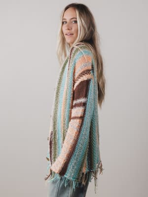 Woman wearing a colorful patterned cardigan against a plain background