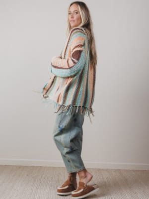 Woman wearing a patterned cardigan and jeans against a plain background