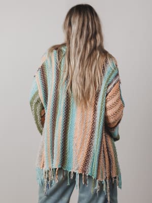 Person wearing a colorful striped shawl with a neutral background