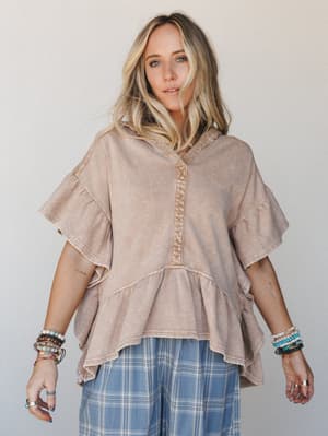 A relaxed, lived-in hoodie tee in washed almond pairs with plaid wide-leg pants — layered with stacks of beaded bracelets and rings for that effortless, collected boho feel.