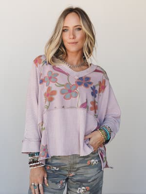 A relaxed mixed-media floral top in soft mauve pairs with camo jeans and stacks of beaded bracelets — the kind of outfit that looks like it came together effortlessly but was absolutely thought about.
